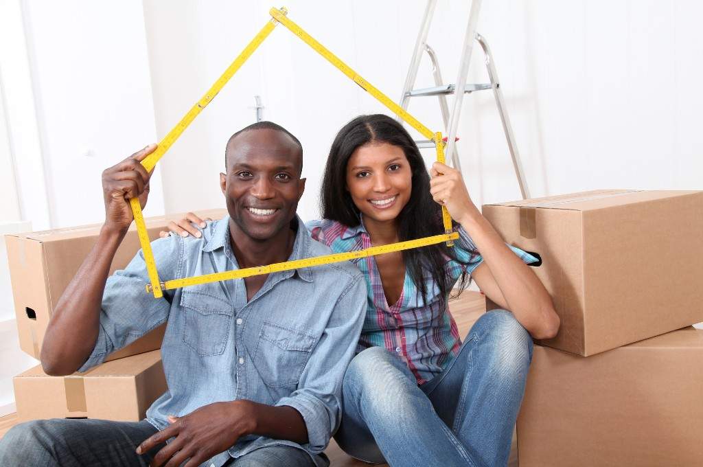 Couple holding a yellow frame shaped like a house