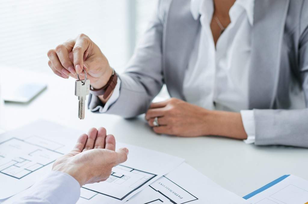 Woman handing a man keys to a home 